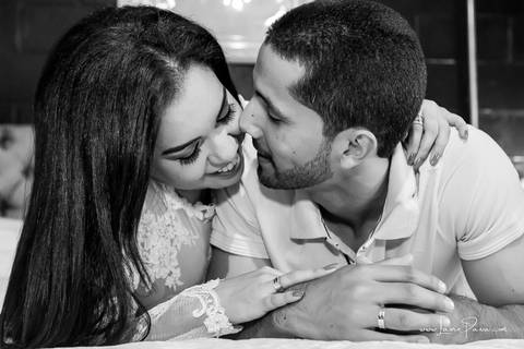 casal deitado na cama com homem dando carinho na mulher que sorrir no quarto do loft de macamirim'