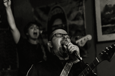 Banda ultra 77 no armazém 77 localizado na zona leste da capital de são paulo. rafael e lilian cantando juntos no palco. rafa pega microfone a frente.'