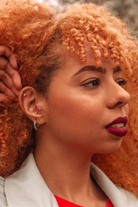 Amanda no parque do carmo, capital de são paulo, na época das cerejeiras. séria sensual, olhando para o horizonte, com a mão segurando o cabelo ruivo.'