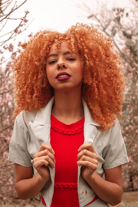 Amanda no parque do carmo, capital de são paulo, na época das cerejeiras. séria sensual, com mãos segurando a roupa em direção a câmera.'
