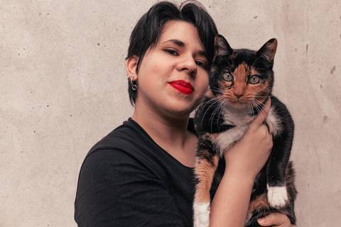 Bianca no quintal da sua casa na zona leste de são paulo. com a gata dela, Joana, em seus braços, ambas olhando para a câmera.'