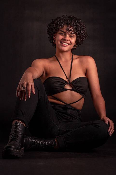 Cássia modelando em estúdio na zona norte da capital de são paulo. sentada no chão. sorrindo.'
