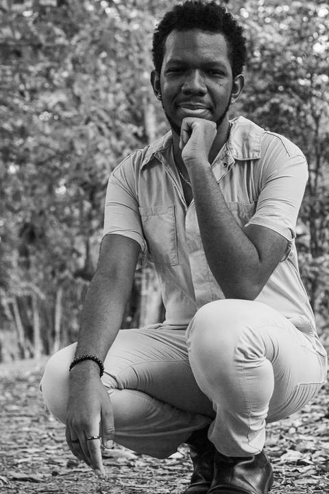 Hugo no parque do carmo, na capital de são paulo. Sorriso leve, enquanto se apoia nas próprias pernas.'