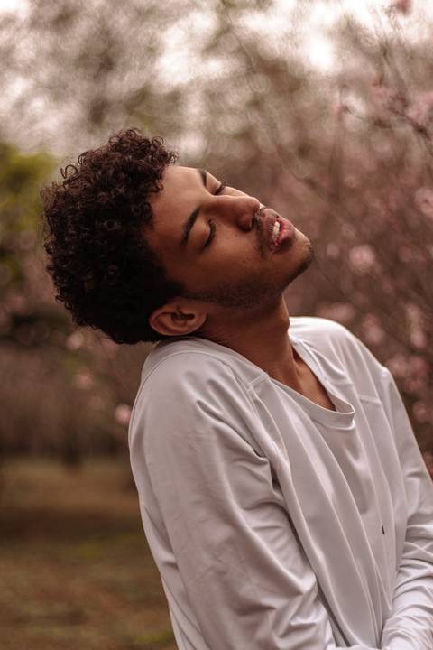 Isaque bailarino, sendo fotografado no parque do carmo na época das cerejeiras, enquanto faz movimento.'