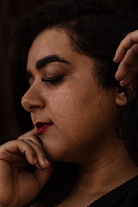 Enquadramento no rosto da Kellen, que está de olhos fechados, enquanto suas mãos estão próximas ao seu rosto.'