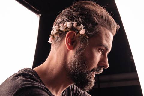Luís registrado em lateral, entre duas fontes de luz, com mini coroa de flores na lateral de sua cabeça.'