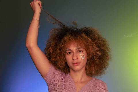 Lariane puxando uma mexa de cabelo para o alto.'