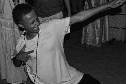 Entidade ajoelhada sob areia com guias.'