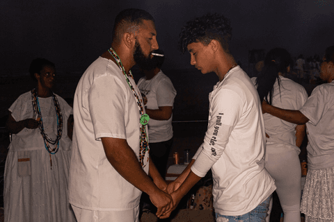 Entidade em contato com fiel e também integrante do terreiro em momento de passe.'