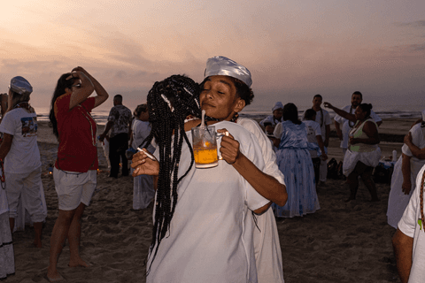 Entidade abraçando integrante do terreiro com copo de cerveja na mão.'