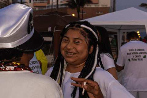 Integrante do terreiro sorrindo ao conversar com entidade.'