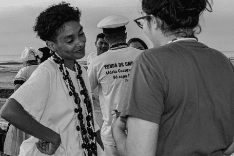 Entidade conversando e sorrindo graciosa com integrante do terreiro.'