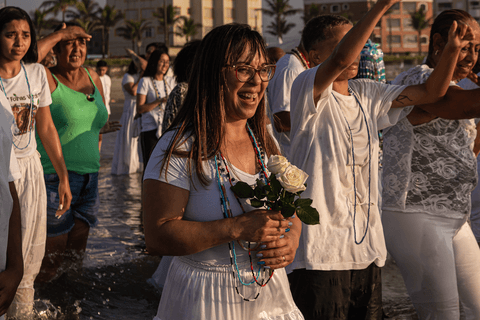 Pessoas sorrindo com flores nas mãos já dentro do mar pela manhã.'