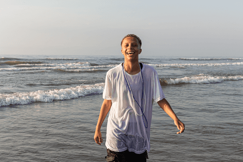 Integrante do terreiro saindo do mar, sorrindo.'