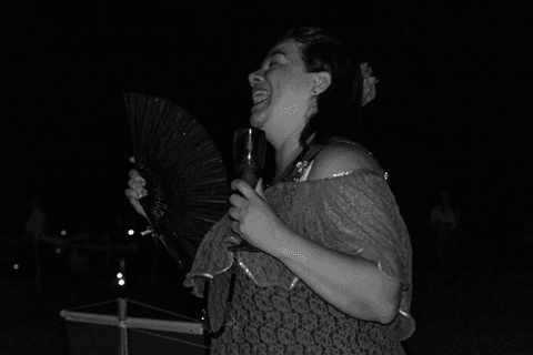 Entidade com taça e leque nas mãos, gargalhando.'