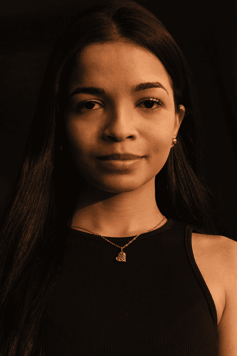 Bruna séria, enquadramento mais fechado, em estúdio com fundo preto.'