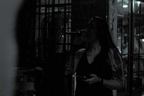 Show da ultra 77 no Armazém 77 ju cantando no vocal, com celular na mção, foto em preto e branco'