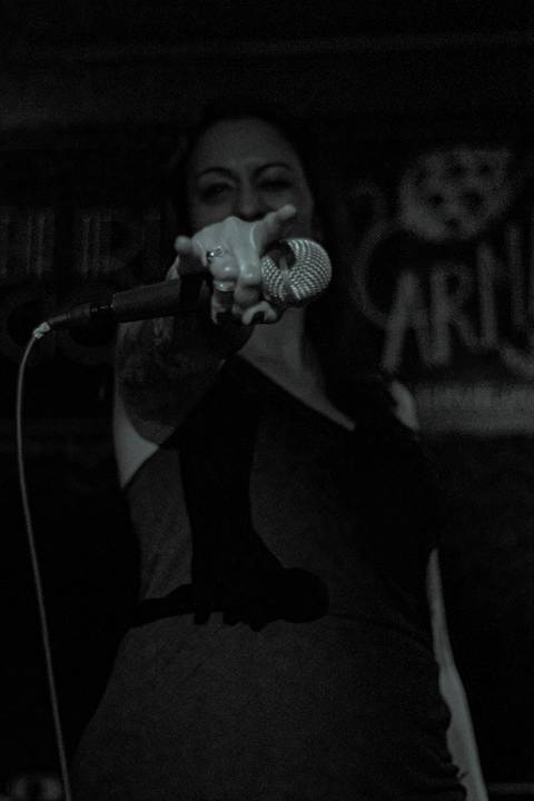 Show da ultra 77 no Armazém 77 juliana cantando com microfone na mão, fazendo careta para a câmera'