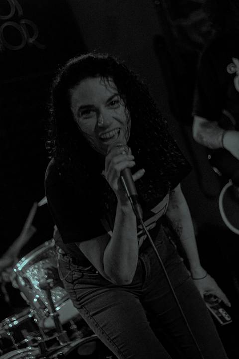 Show da ultra 77 no Armazém 77 renata no vocal, olhando diretamente para a câmera, foto em preto e branco, sorrindo'