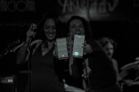 Show da ultra 77 no Armazém 77 juliana e renata mostrando a letra da música em seus celulares, sorrindo'