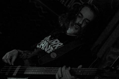 Show da ultra 77 no Armazém 77 luciano com cabelos em seu rosto, tocando seu instrumento'