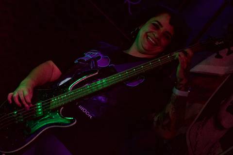 Show da ultra 77 no Armazém 77 aline olhando para seu baixo enquanto toca, sorrindo'