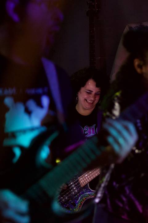 Show da ultra 77 no Armazém 77 aline no meio de rafael e renata, sorrindo enquanto olha para baixo'