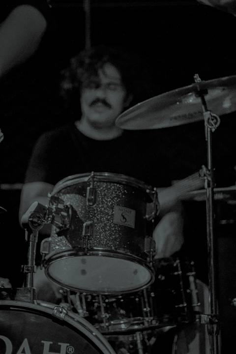 Show da ultra 77 no Armazém 77 edu na bateria tocando, enquanto o foco da foto esta em sua bateria'