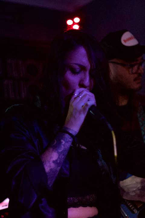 Show da ultra 77 no Armazém 77 juliana cantando no vocal, luz rosa e rosa, ângulo mais próximo do objeto'