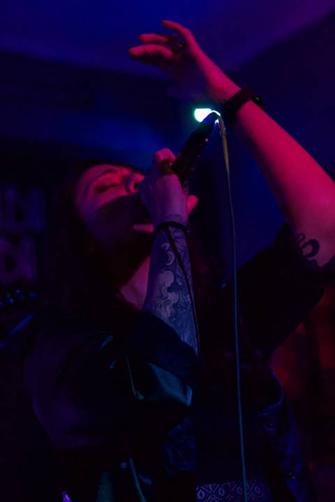 Show da ultra 77 no Armazém 77 juliana cantando, com os ohlos fechados e mão para cima, iluminação roxa e rosa'