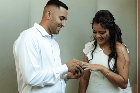 casamento no civil bárbara e guilherme trocando alianças olhando para as aliança enquanto sorriem'