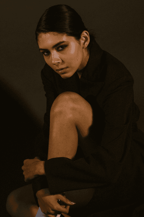 bia sentada, abraçando suas pernas, fotografia colorida'