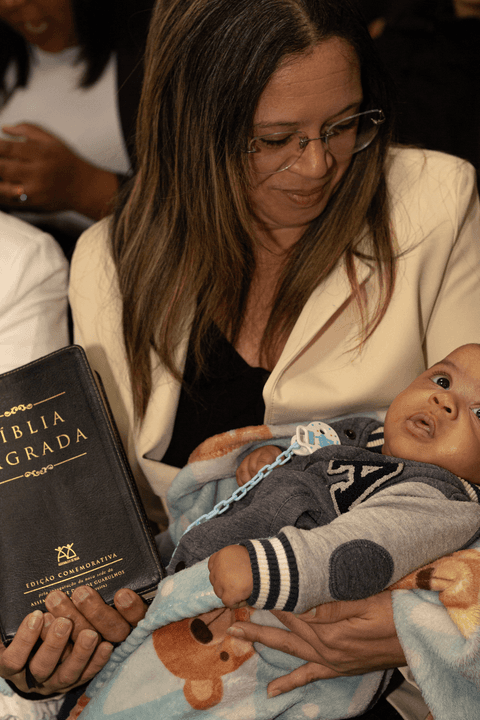 Bryan com sua mãe no colo dentro da igreja, com a biblía em mãos'