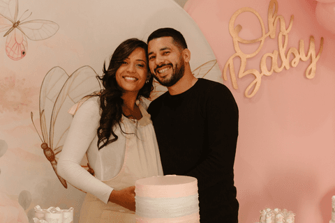chá de bebê da maya pais de maya se abraçam em frente a decoração'