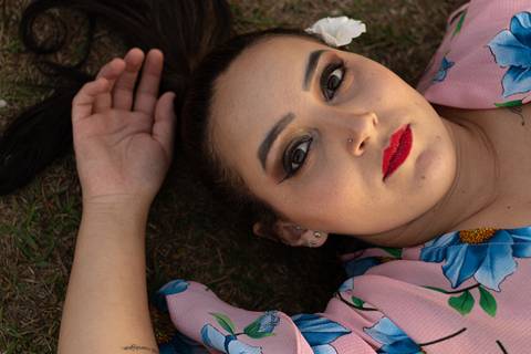 isabel deitada na grama com uma flor no cabelo'