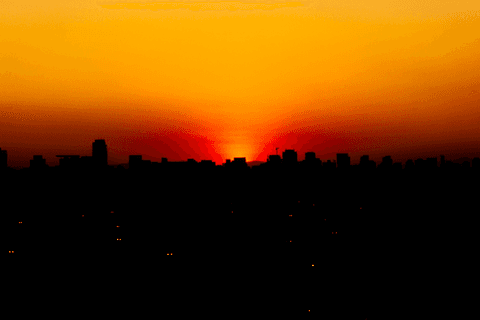 jerf no terraço do mac pôr do sol forte, meio céu meio cidade, sol quase sumindo de vista atrás dos prédios'