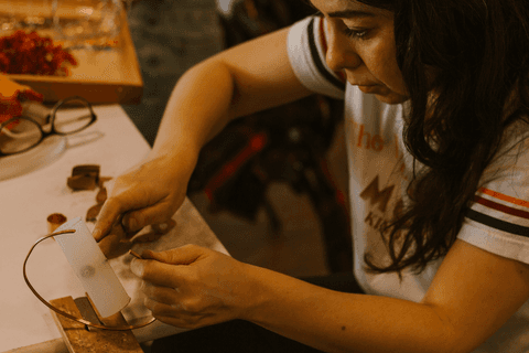 sesc paulista oficina de criação de jóais, aluna batendo com o martelo no ferro para moldar parte de sua jóia'