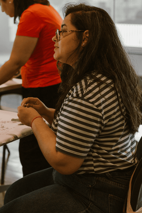 sesc paulista oficina de criação de jóais, uma outra aluna trabalhando enquanto está sentada, olhando para a frente com suas peças em mãos'