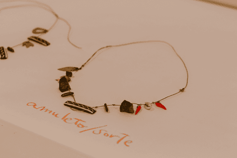 sesc paulista oficina de criação de jóais, um dos amuletos concluído sobre a mesa, com cartolina com as escrituras da aluna'