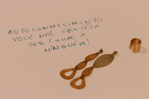 sesc paulista oficina de criação de jóais, brincos e anel criado por aluna já sobre a mesa e cartolina com frase escrita'