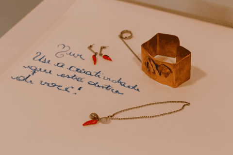 sesc paulista oficina de criação de jóais, colar e pulseira criados por aluna sobre mesa, em cima da cartolina com a frase escolhida pela aluna escrito nela'