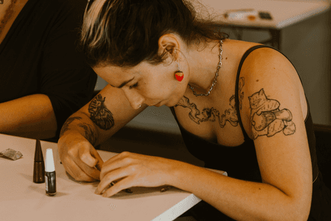 sesc paulista oficina de criação de jóais, aluna apoiada a mesa trabalhando na sua peça'