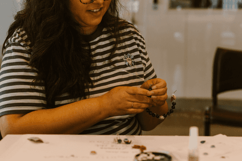sesc paulista oficina de criação de jóais, aluna sorrindo enquanto olha para suas criações'