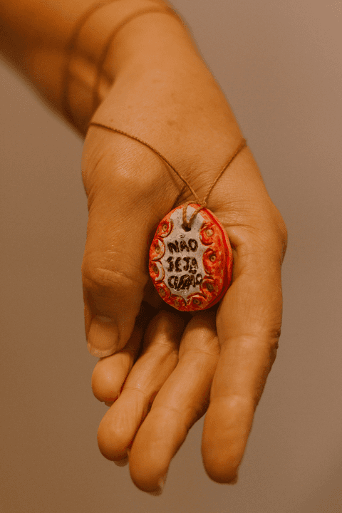 sesc paulista oficina de criação de jóais, colar finalizado pela aluna em sua mão escrito 