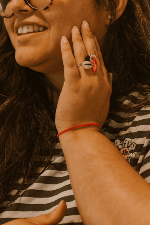 sesc paulista oficina de criação de jóais, aluna com a mão sobre seu rosto, sorrindo enquanto mostra seus anéis'