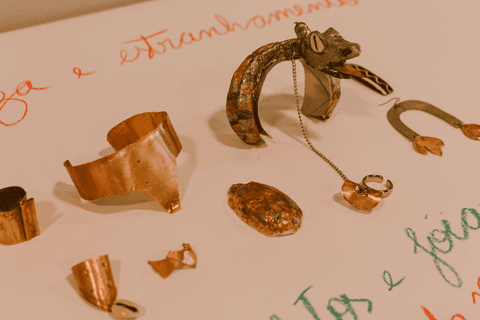 sesc paulista oficina de criação de jóais, muitas jóias criadas por uma das alunas sobre a mesa, cartolina e sua frase essencial, entre brincos, anéis, colares e braceletes'