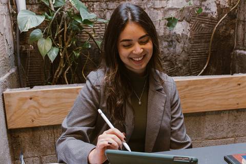 ni sozinha na foto, enquanto trabalha no tablet, sorrindo'