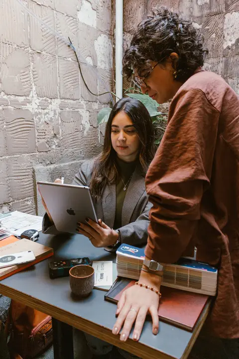 le e ni juntas, le em pé ao lado de ni que esta sentada na cadeira, em seu tablet'