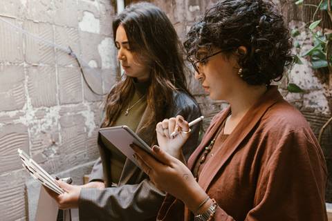 ambas em pé fazendo análises em seus documentos'