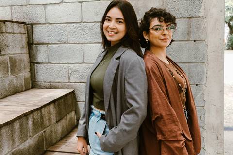 le e ni na escadaria da cafeteria ao lado de fora ambas em pé uma ao lado da outra encostando costa com costa'